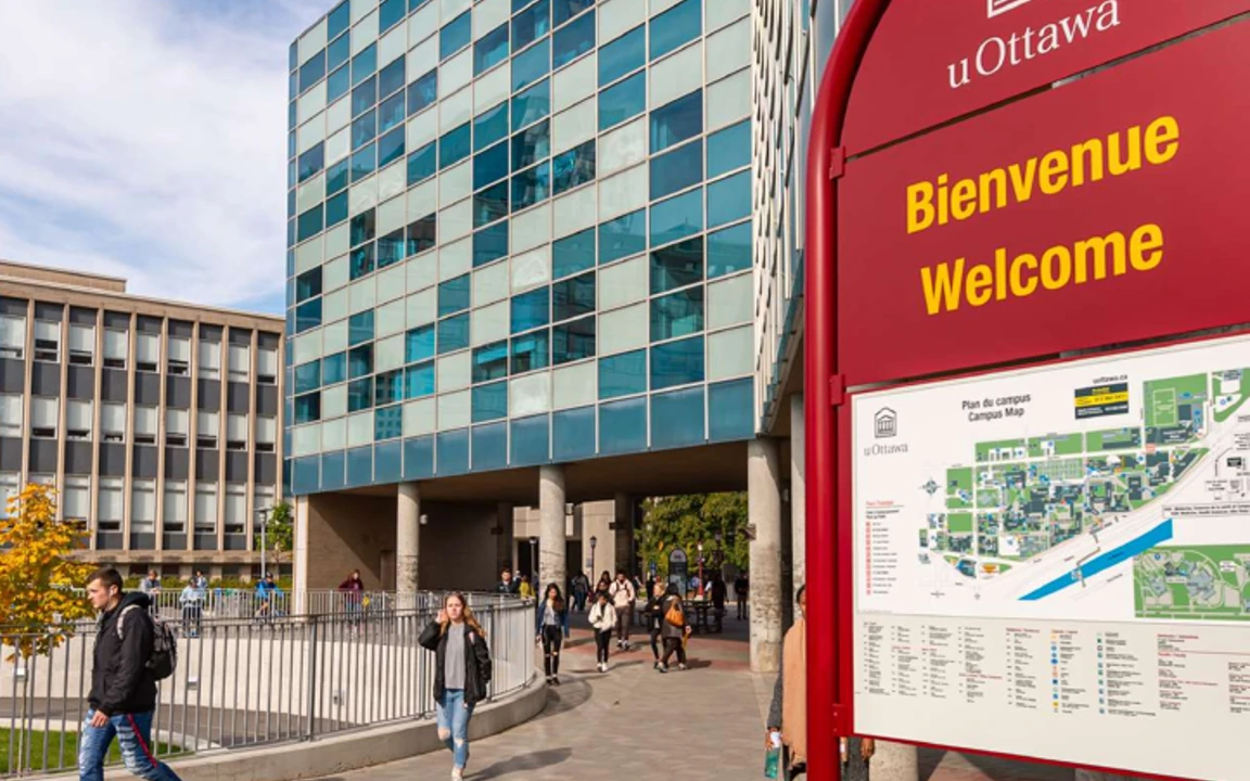 façade d'un pavillon de l'université d'Ottawa, avec une affiche arrondie qui indique Bienvenue, avec une carte du campus